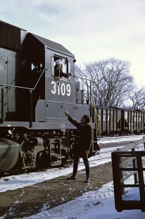 Ann Arbor Operator Botkin hands up orders to eastbound JT-3 headed by Penn Central GP-40 No.3109 on 12 January 1969.  JT-3 was a freight that ran from Jackson, Michigan to Toledo, Ohio. Photograph by William Botkin, BOTKINW-10-WT-181 © 1969, William Botkin.