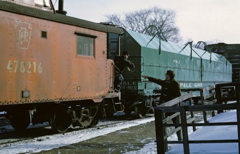 Operator Botkin hands up orders to the conductor on eastbound JT-3 (Jackson-Toledo) in Ann Arbor, Michigan on 12 January 1969.  Almost a year after the Penn Central merger, caboose No.478216 is still in its PRR livery.