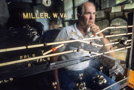 Tower operator Jim Vargo assesses the control board at the B&O Miller Tower in Cherry Run, West Virginia, on July 22, 2000.

Judges’ Comments: A superb portrait of a tower operator pondering an uncertain future reflected in the control machine, which tells its own story in electrical tape and paint presenting the evolution of physical plant, as how the railroad is now able to do more with less, or in many circumstances, simply do less. This image offers the viewer a visual window into the shifting dynamics and ever-changing landscape of rail transportation that forms an exquisite piece of photojournalism. 

Read more about the 2023 John E. Gruber Creative Photography Awards: <a href="https://railphoto-art.org/awards-2023/" rel="noreferrer nofollow">railphoto-art.org/awards-2023/</a>