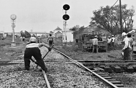 Track crew puts finishing touches on Missouri–Kansas–Texas Railroad crossing as northbound Missouri Pacific Railroad freight train waits in July 1965. Photograph by J. Parker Lamb, © 2016, Center for Railroad Photography and Art. Lamb-02-062-10