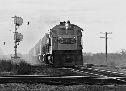 Northbound Atchison, Topeka and Santa Fe Railway freight approaches Missouri Pacific Railroad crossing at Milano, Texas, in February 1971 (rear of train right background). Photograph by J. Parker Lamb, © 2016, Center for Railroad Photography and Art. Lamb-02-067-03