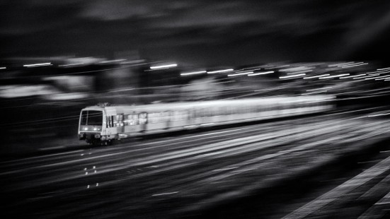 RER B train en route to Roissy Charles de Gaulle airport as it passes through Le Bourget in the northern suburbs of Paris, France, on a January 2012 evening. The photographer is a train driver in France and to him, "trains are synonymous with shakings, jumpings, etc. This was picture was done at slow speed and using a derivative of the classical panning technique. As the train goes away from a 45-degree angle, a small part of it is sharp." He used Nik Silver Efex Pro 2 software to convert image from color to B&W after initial processing in Adobe Lightroom.