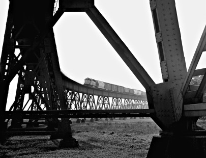 Northbound Kansas City Southern Railway freight train heads downgrade on west side of Mississippi River bridge on a foggy morning of April 1969. This view emphasizes the mammoth scale of such large structures in relation to railway equipment. Photograph by J. Parker Lamb, © 2016, Center for Railroad Photography and Art. Lamb-02-071-06