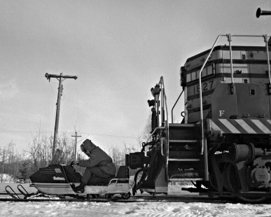 Rider on Arctic Cat Panther snowmobile posing in front of Alaska Railroad EMD GP7L locomotive no. 1827, c. 1973. Photograph from the Leo King Collection, Center for Railroad Photography and Art. King-03-060-012