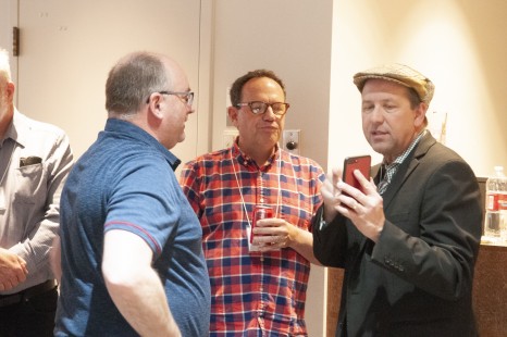 Thomas Hillebrant, James Belmont, and Elrond Lawrence share photos during a break on Saturday at Conversations Transcontinental. Photograph by Hank A. Koshollek.