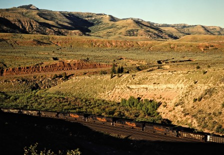 Westbound coal train climbing the Denver and Rio Grande Western's grade up Soldier Summit near Kyune, Utah, on July 7, 1993, with the assistance of these four mid-train helper locomotives. This is technically a Southern Pacific train—the Rio Grande acquired the much larger SP in 1988, but retained the name of the bigger road. Photograph by John F. Bjorklund, © 2015, Center for Railroad Photography and Art. Bjorklund-49-14-10