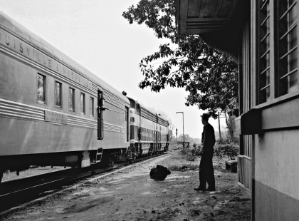 Operator at village of Loachapoka, Alabama (near Auburn), watches eastbound West Point Route <i>Crescent</i> passenger train as it races past station in March 1955. (Note: that falling mail bag was recorded only inches from the ground.) Photograph by J. Parker Lamb, © 2016, Center for Railroad Photography and Art. Lamb-02-020-07