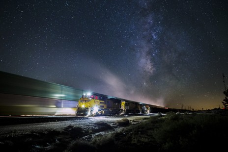 Beneath a clear sky filled with thousands of stars in the Milky Way, an eastbound empty hopper train waits at Cima, CA for a passing intermodal.