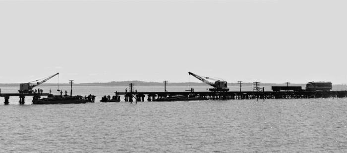 During the 1950s, the 140-mile Louisville and Nashville Railroad line between Mobile and New Orleans contained around twenty-five miles of timber trestles, which could easily ignite from sparks produced by brakes or hotboxes. This scene on Biloxi Bay, Mississippi, in 1955 shows construction crews working from both ends of a break to speed up the repair. Photograph by J. Parker Lamb, © 2016, Center for Railroad Photography and Art. Lamb-01-151-06
