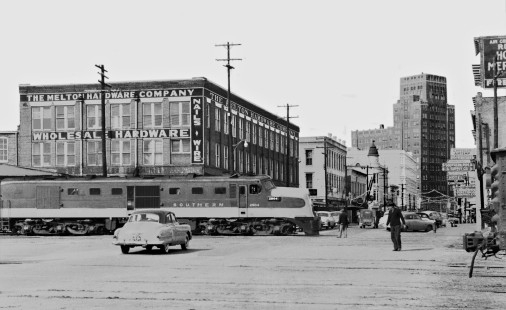 Alco DL-109 eases across 22nd Avenue in downtown Meridian, Mississippi, in December 1954, with Birmingham-bound <i>Queen & Crescent</i> passenger train no. 44, a few hundred feet from the Meridian Union Station. (Note: tall building built by Dryfuss brothers from Germany in the 1930s, known locally as Threefoot Building.) Photograph by J. Parker Lamb, © 2016, Center for Railroad Photography and Art. Lamb-01-107-04