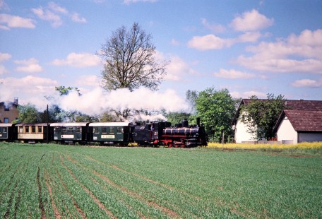 Waldviertler Narrow-Gauge Railway Club 0-8-4 steam locomotive no. 399.04 travels along the edges of a cultivated field in Gmünd, Lower Austria, Austria, on May 12, 2001. Photograph by Fred M. Springer, © 2014, Center for Railroad Photography and Art. Springer-Austria-03-32