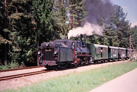 Several riders look out the passenger car doors as Waldviertler Narrow-Gauge Railway Club steam locomotive no. 399.04 moves down the track in Nagelberg, Brand-Nagelberg, Austria, on May 12, 2001. Photograph by Fred M. Springer, © 2014, Center for Railroad Photography and Art. Springer-Austria-03-02